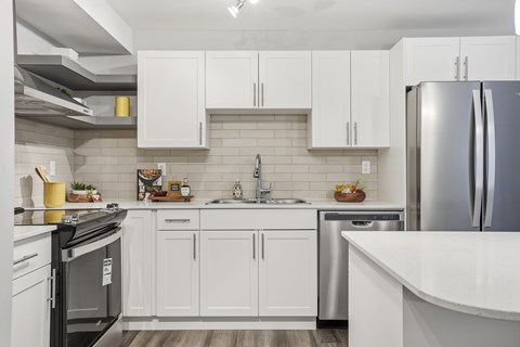 A modern kitchen with white cabinets and stainless steel appliances.