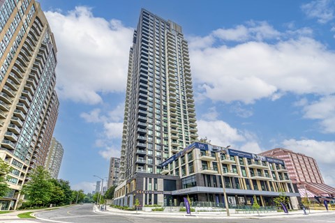 A tall building with a curved facade stands in front of two other buildings.