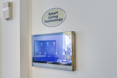 A wall-mounted smart TV with a sign above it that reads "Smart Living Technology".