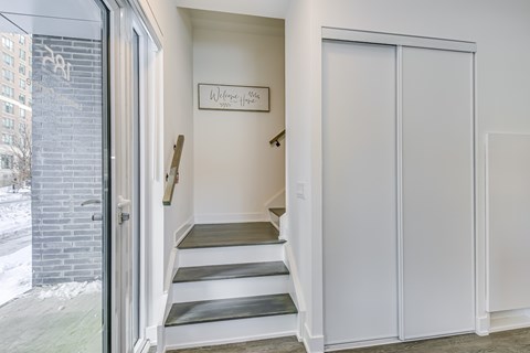 A white door with a glass window is open to a hallway.