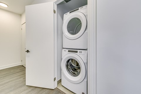 A white washing machine is in a white cabinet.