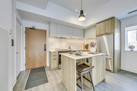 A kitchen with a wooden bar stool in front of the counter.