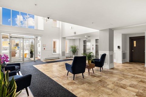 A spacious lobby with black chairs and a wooden floor.