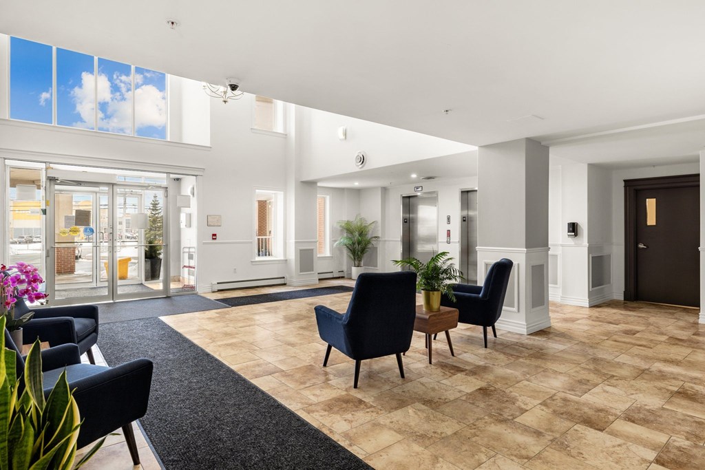 A spacious lobby with black chairs and a wooden floor.