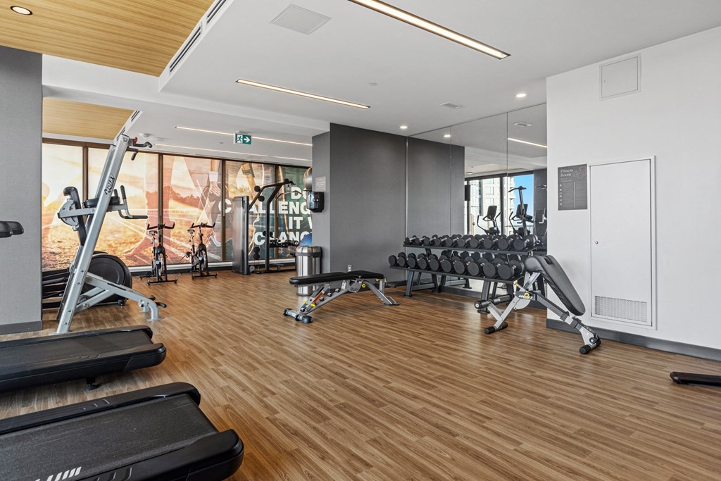 a gym with cardio machines and weights on a wooden floor