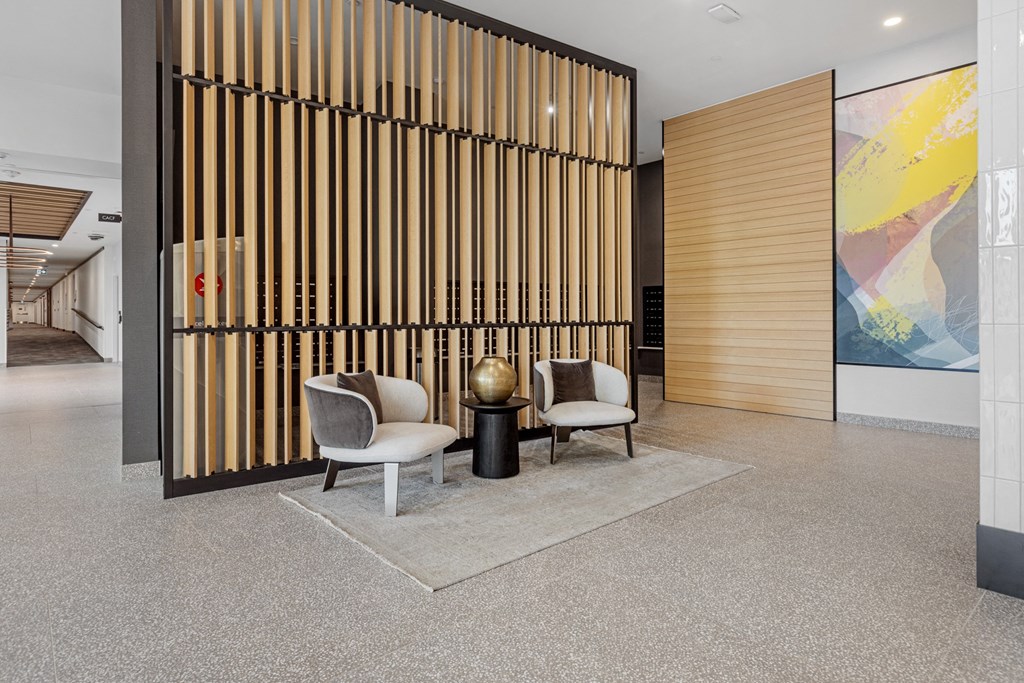 a lobby with two chairs and a table in front of a wooden screen