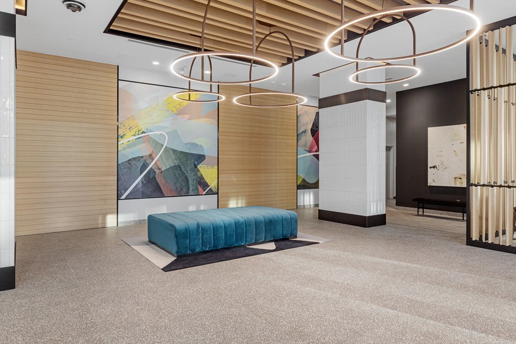 a lobby with a blue bench and a large painting on the wall