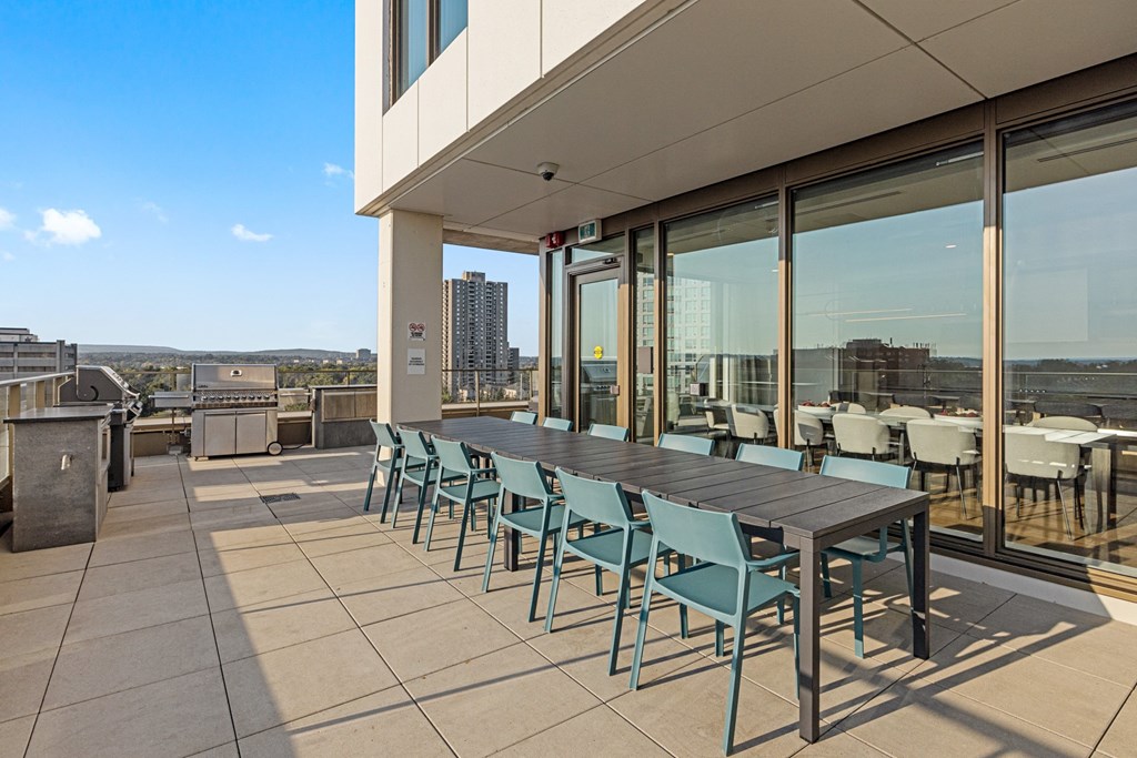 a communal table and chairs on the terrace of a building