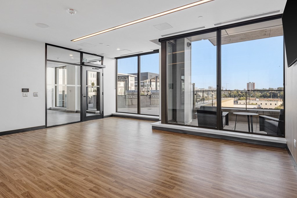 a living room with wood floors and glass windows and a balcony