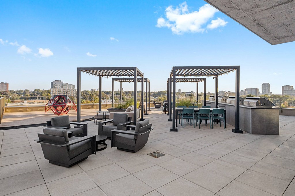 a rooftop patio with chairs and tables and a city in the background