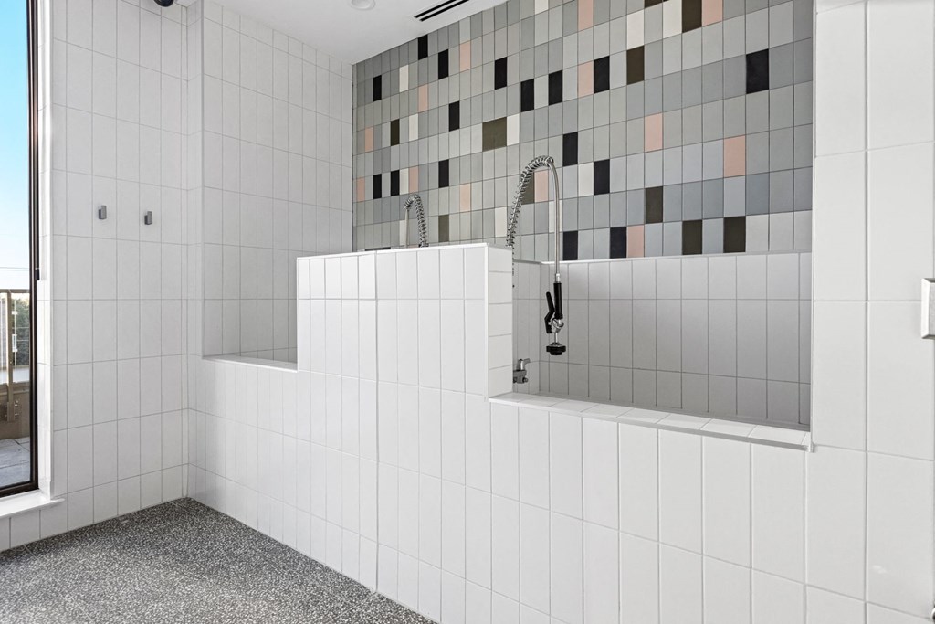 a white tiled bathroom with a shower and a sink