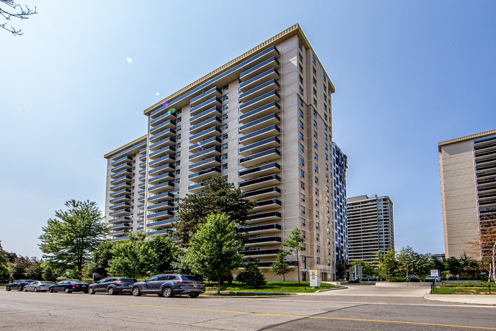 A tall residential building with a parking lot in front.