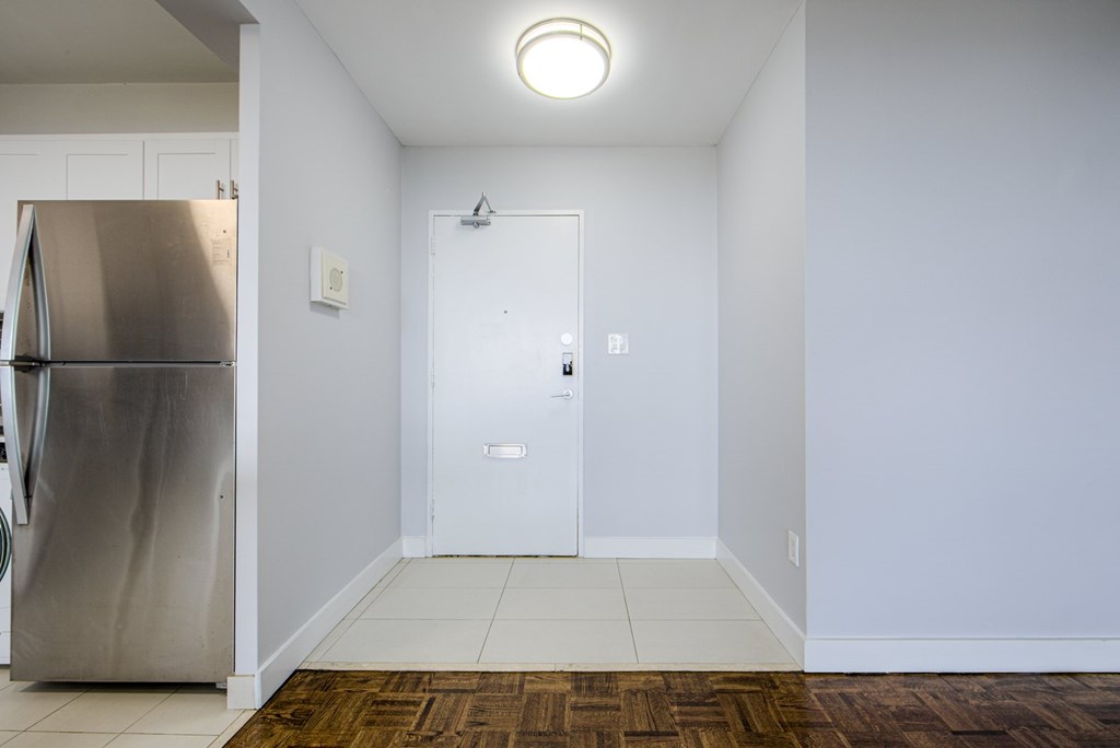 A kitchen with a white door and a stainless steel refrigerator.
