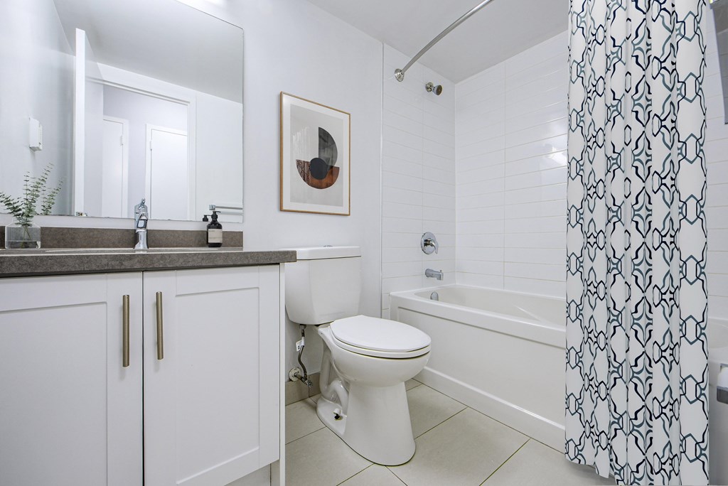 A white bathroom with a toilet, sink, and shower.