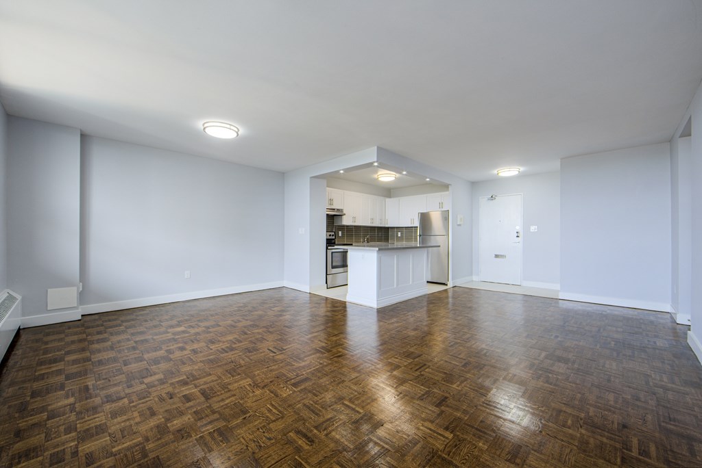A large empty room with wooden flooring and white walls.