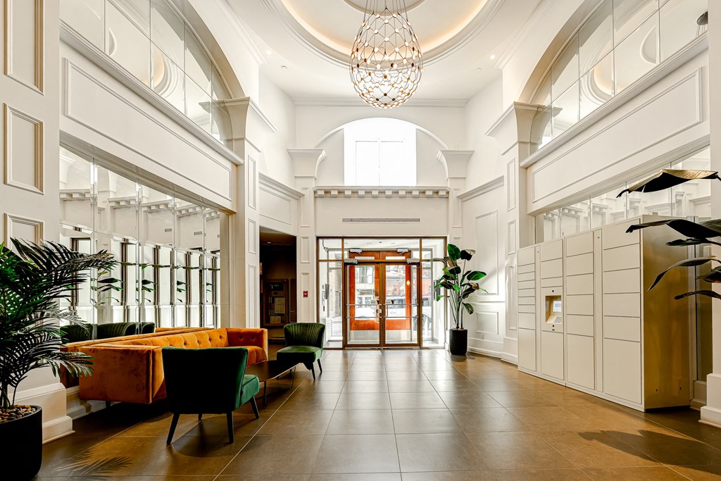 The lobby with a chandelier, a long table with chairs, and a plant in a black pot at Le Demetrius.
