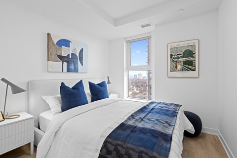 A bedroom with a white bed and a blue and white patterned blanket.