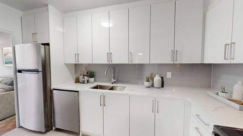 a white kitchen with white cabinets and a stainless steel refrigerator