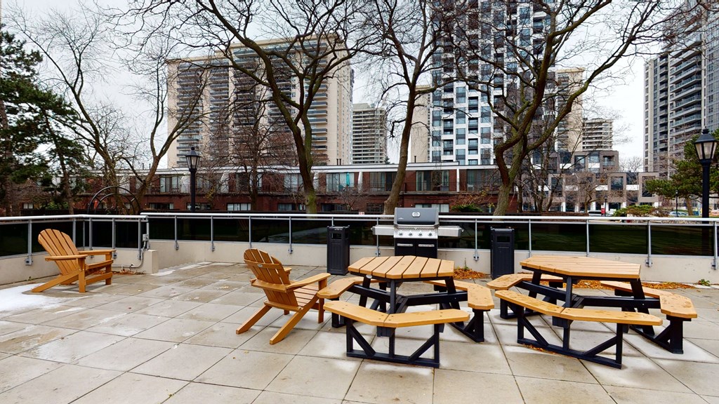 A patio with wooden chairs and tables is empty.