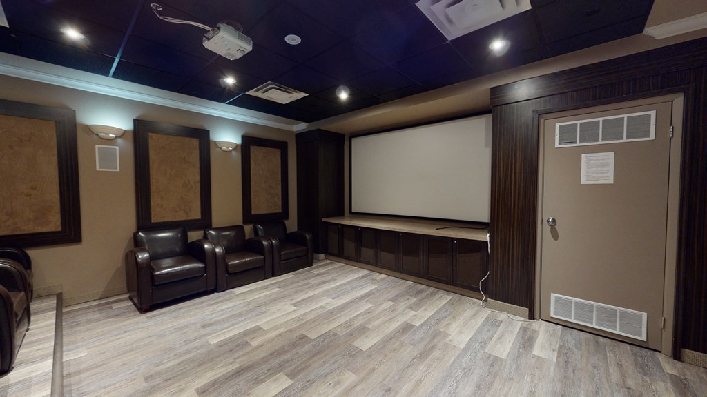 a dark room with a projector screen and leather chairs