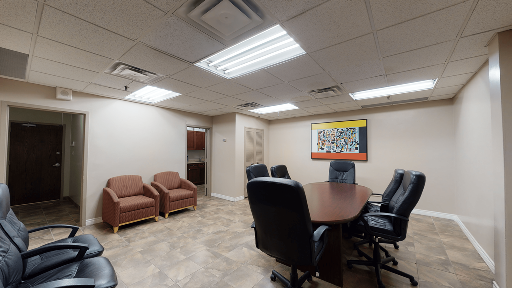 A conference room with a table, chairs, and a painting on the wall.