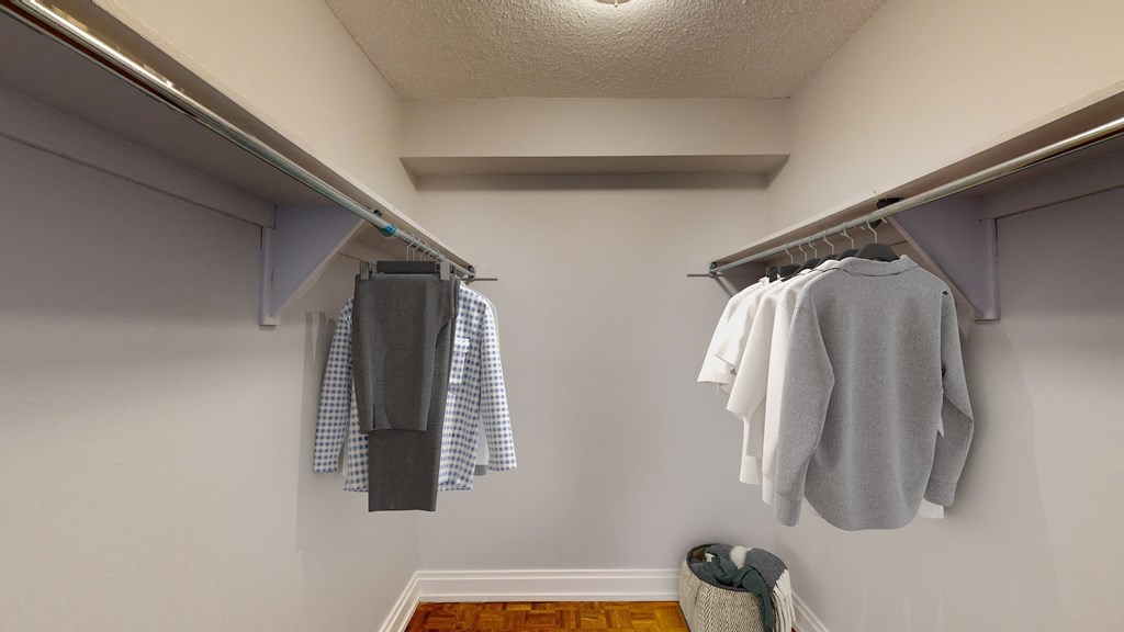 A room with a checkered shirt hanging on the left and a grey shirt hanging on the right.