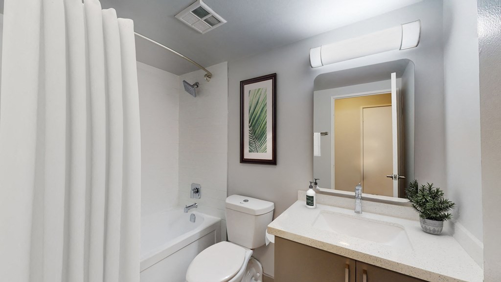 A white bathroom with a toilet, sink, and shower.