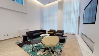 A living room with a black couch, a white chair, and a rug.