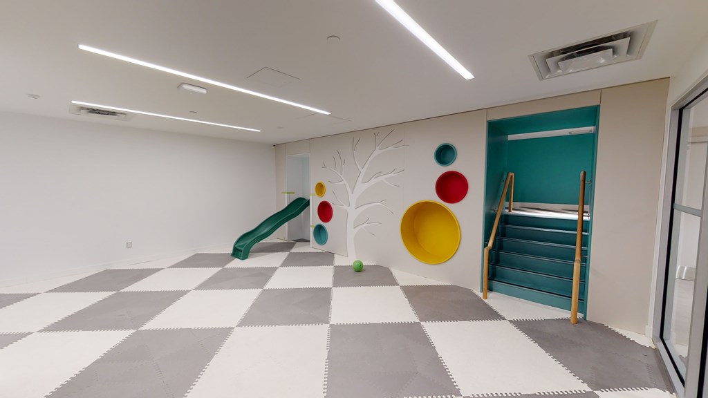 A play area with a slide and a tree design on the wall.
