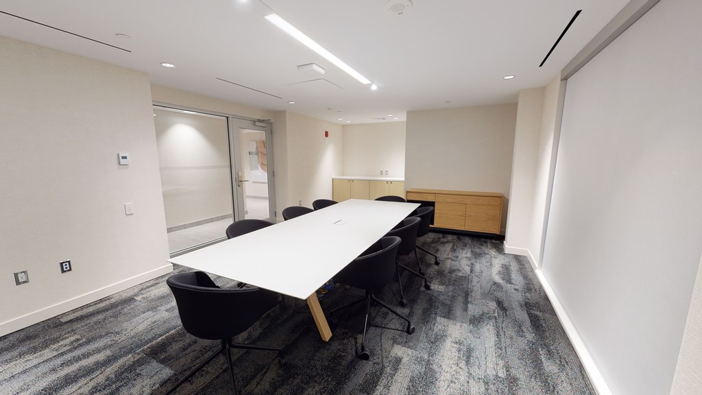 A conference room with a long table and chairs.