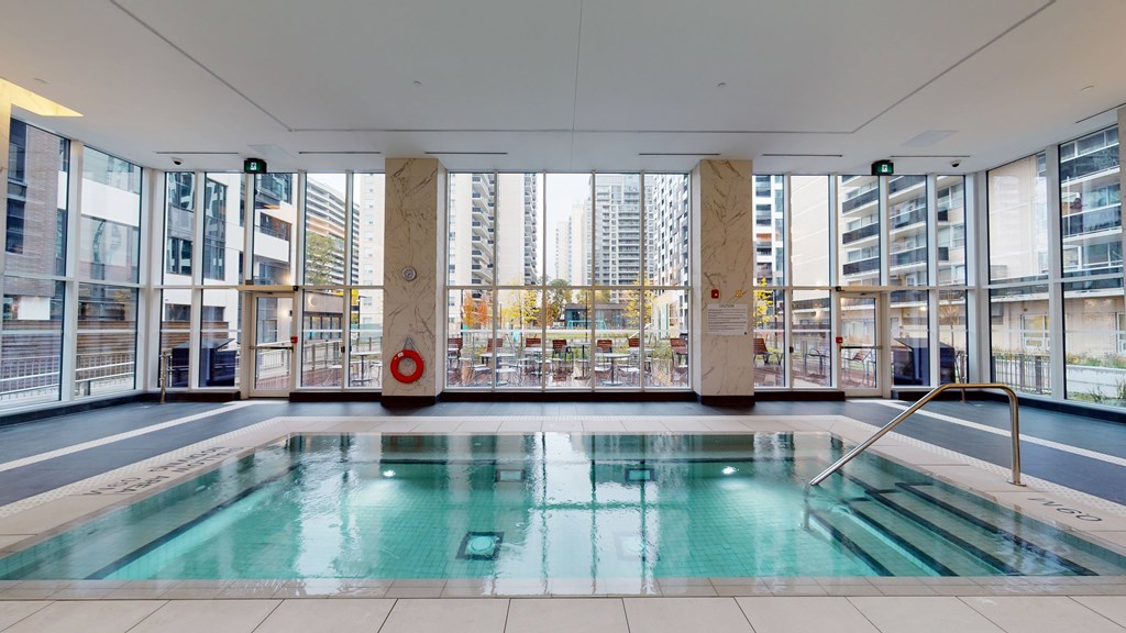 A large indoor swimming pool with a view of the city outside the windows.