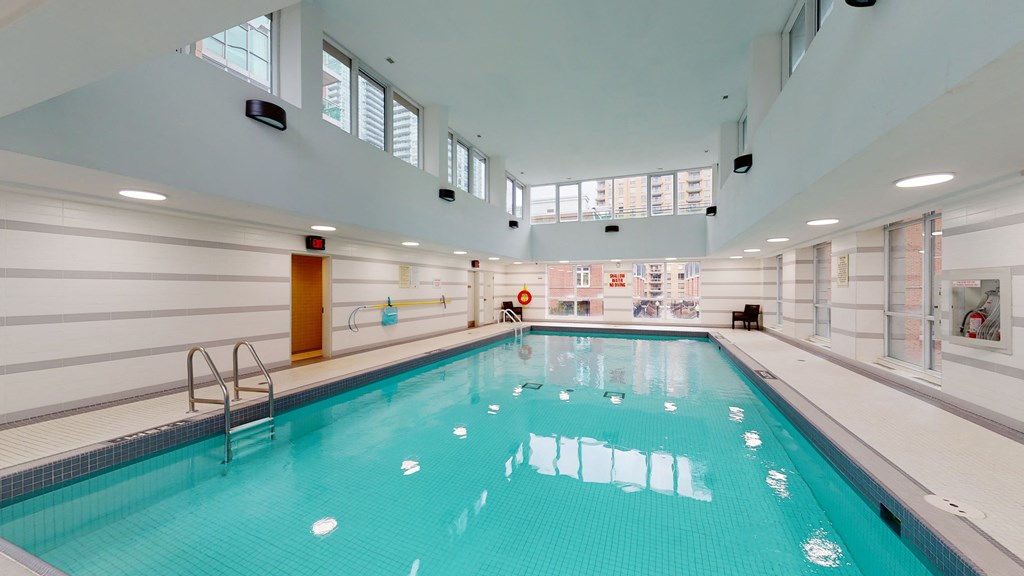 a swimming pool in a large room with windows on the walls