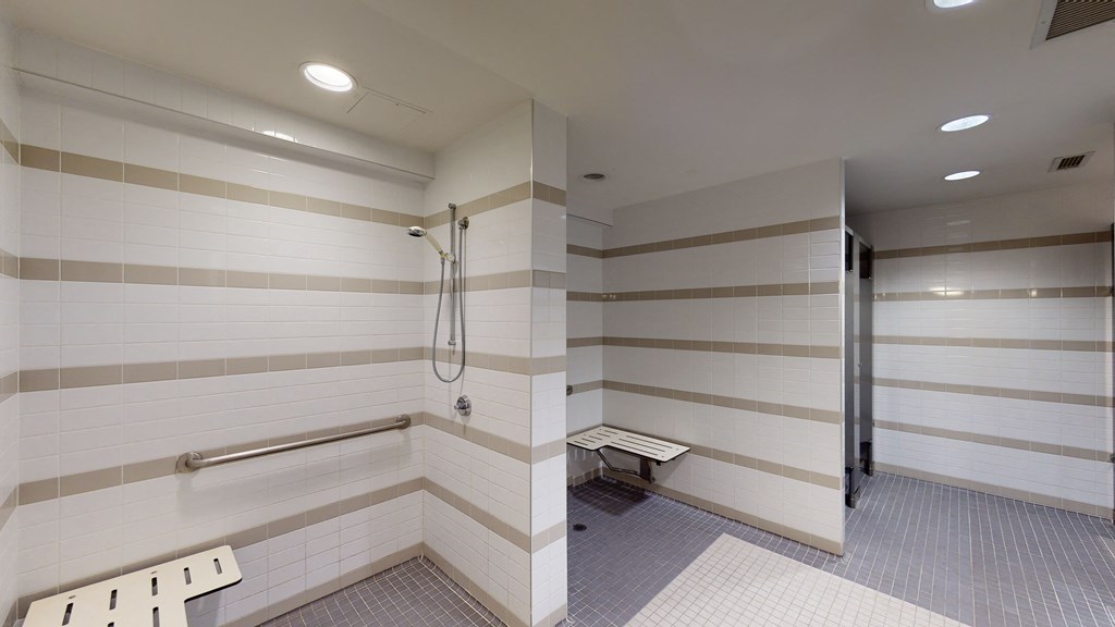 a large white tiled bathroom with a shower and a bench