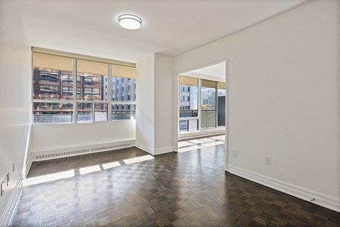 an empty living room with a large window and wood flooring