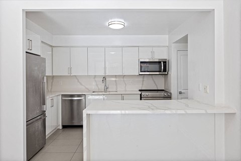 a white kitchen with a counter top and a refrigerator