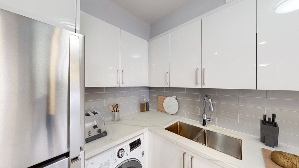 A modern kitchen with a stainless steel refrigerator and white cabinets.