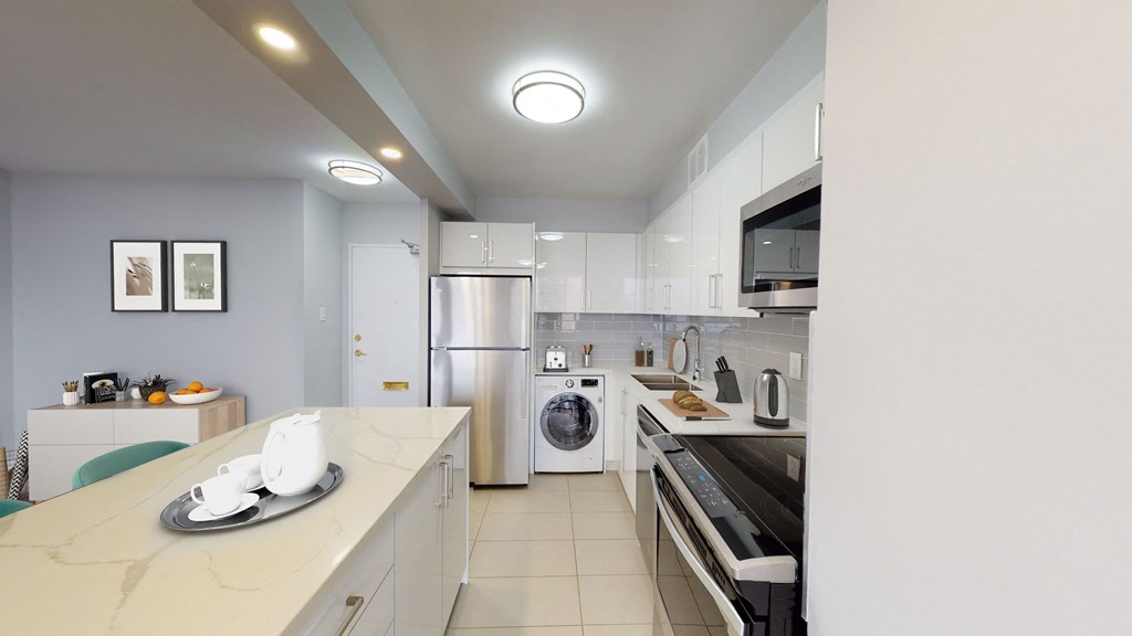 A modern kitchen with a marble countertop and stainless steel appliances.