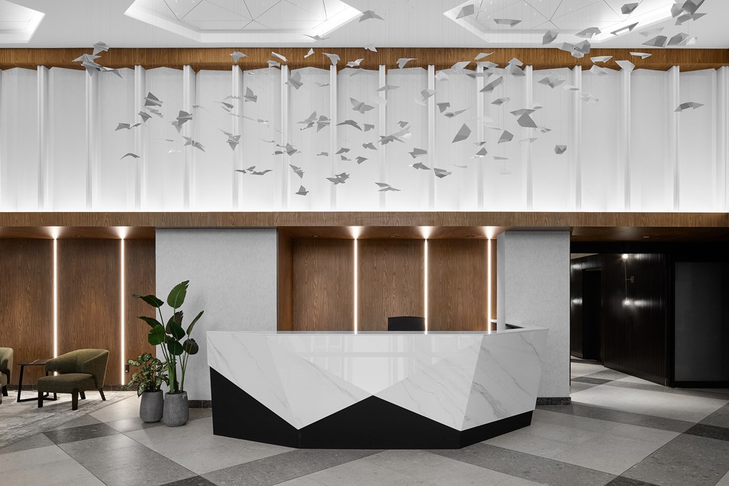 A reception area with a white and black reception desk and a wall of windows.