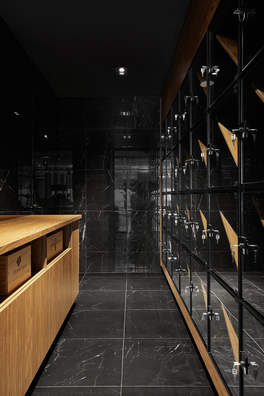 A long hallway with a black marble floor and wooden furniture.