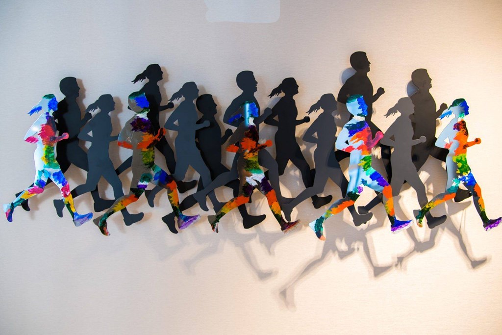 A wall of paper cut outs of people running.
