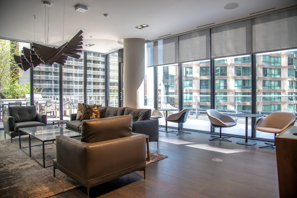 A modern living room with a large window and a variety of chairs and couches.