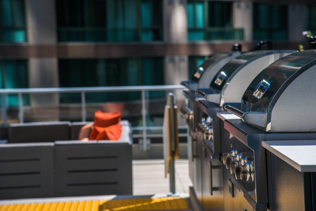 A row of outdoor grills are lined up on a patio.