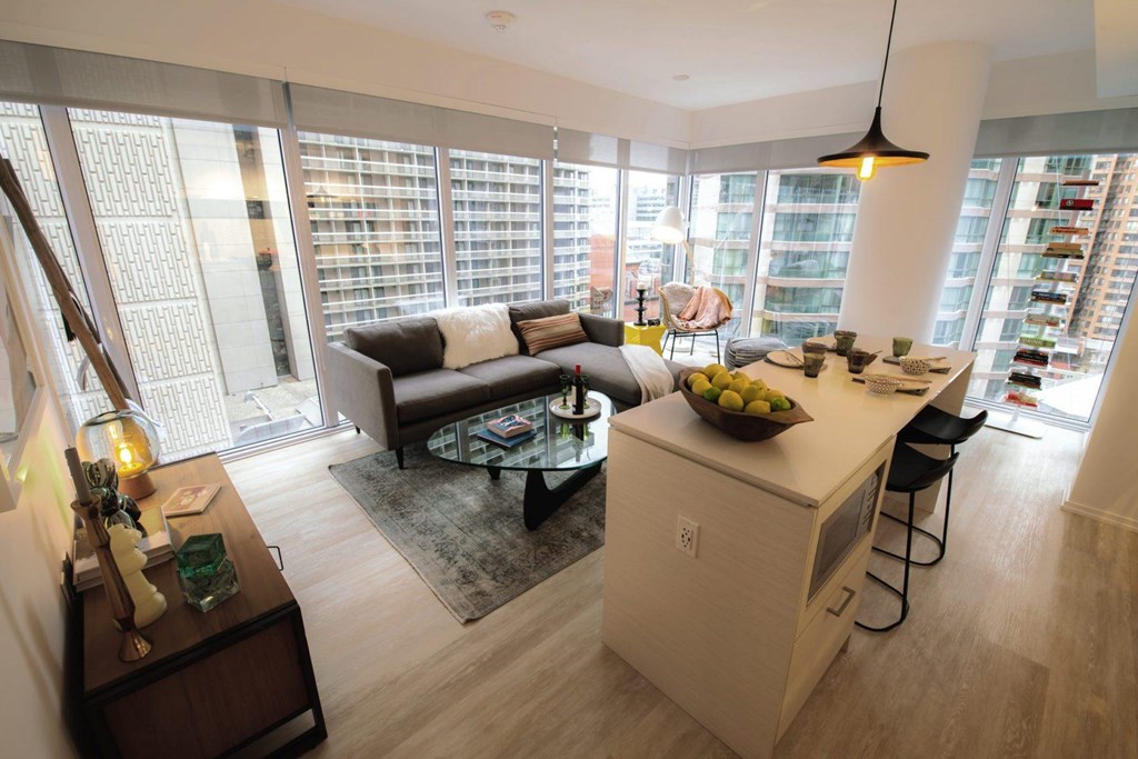 A modern living room with a large window and a kitchen area.
