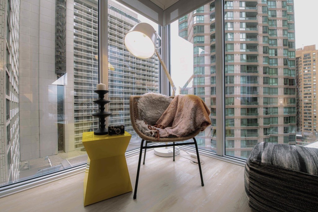 A chair with a brown blanket on it is in front of a window with a view of a city.
