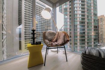 A chair with a brown blanket on it is in front of a window with a view of a city.