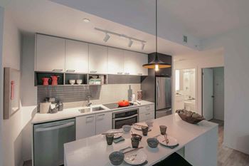 A modern kitchen with a white countertop and stainless steel appliances.
