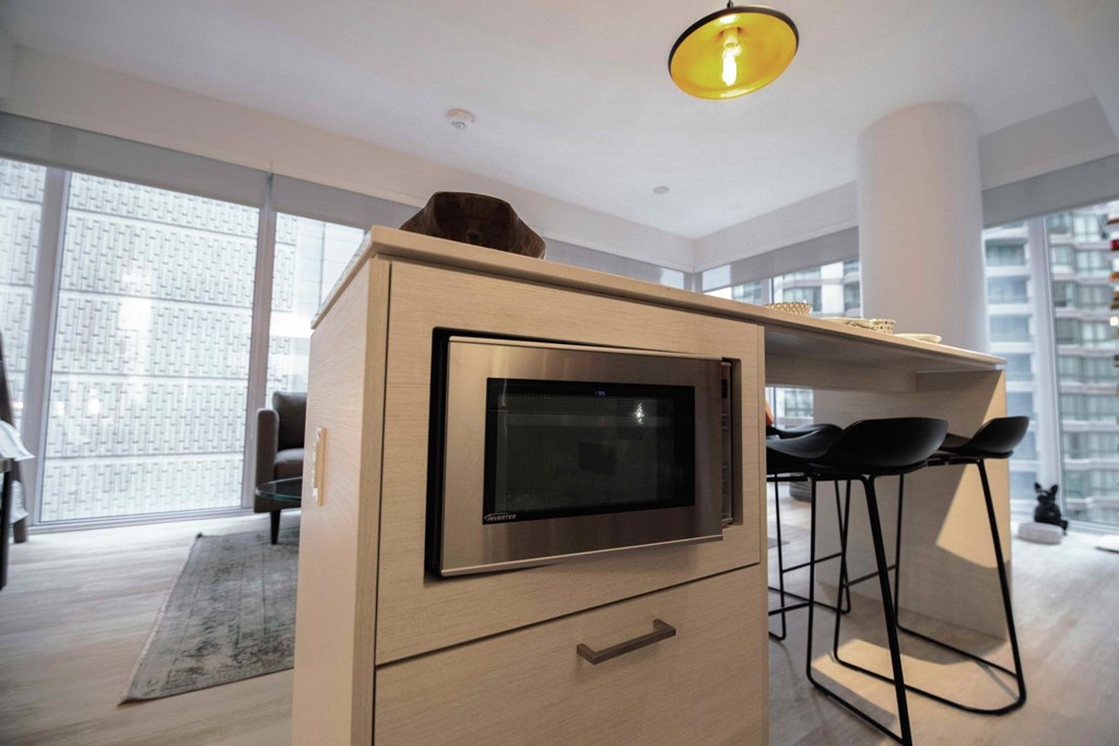 A modern kitchen with a wooden cabinet and a microwave.