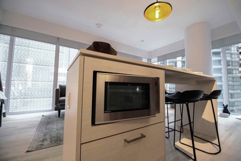 A modern kitchen with a wooden cabinet and a microwave.