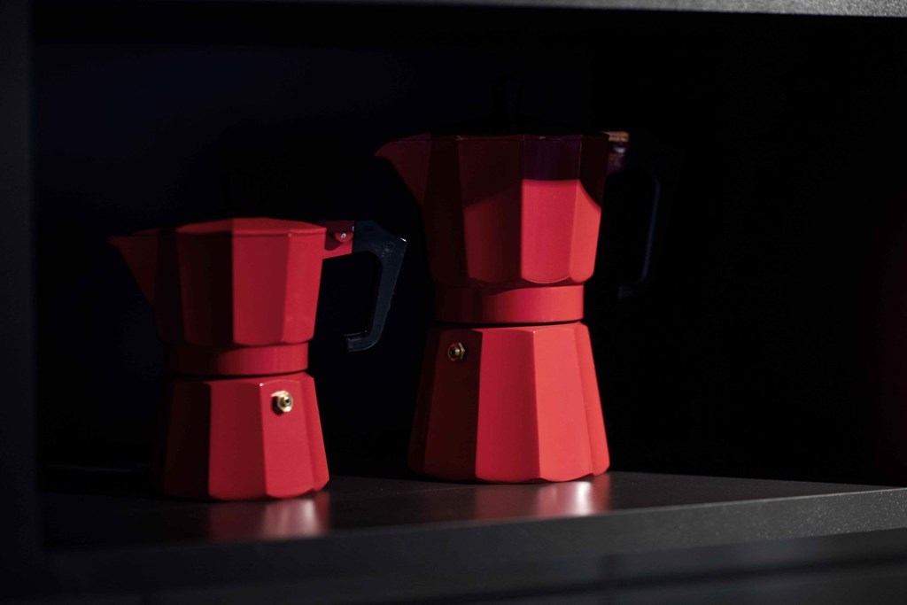 Two red coffee pots on a black surface.