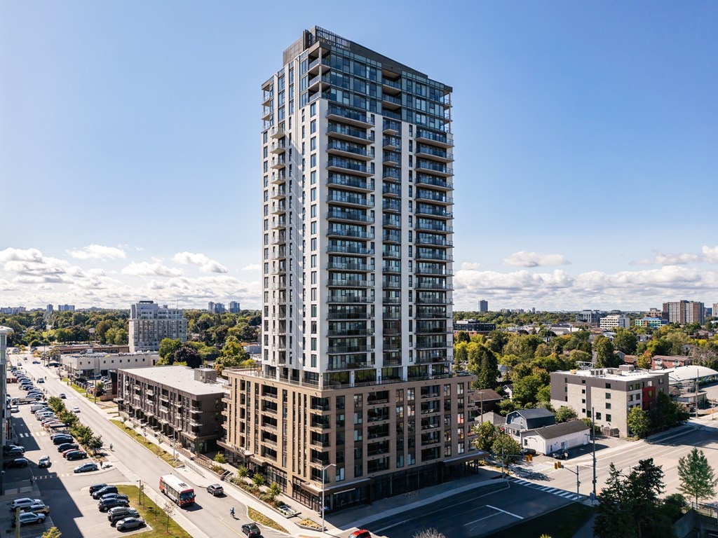 A tall building with many windows stands in the middle of a city street.